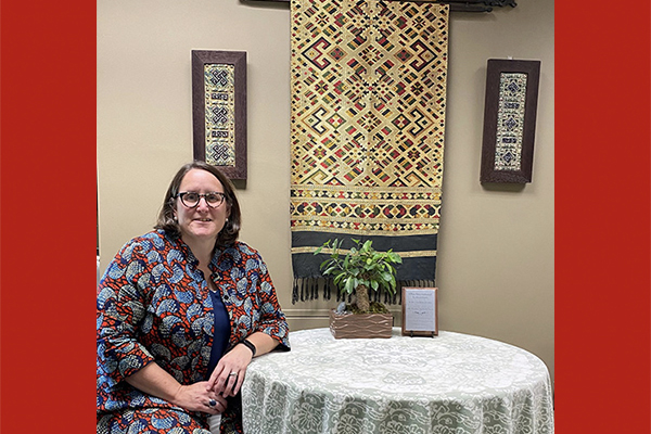 Karla Guinigundo sits in her office in front of a woven Vietnamese scarf.